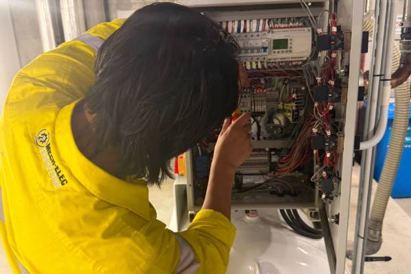 Industrial electrician inspecting electrical control panel equipment onsite